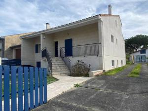 una casa blanca con una valla azul delante de ella en Belle villa avec grande piscine 12 couchages 100m du tram, en Le Bouscat