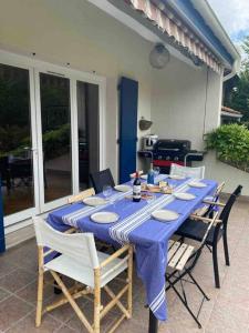 einen Tisch mit Stühlen und einem blauen Tischtuch in der Unterkunft Belle villa avec grande piscine 12 couchages 100m du tram in Le Bouscat