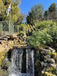 a waterfall in a garden with a bridge and a creek at מון-שיר הגושרים in Hagoshrim