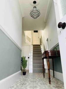 a hallway with a staircase and a piano in a house at Beautifully restored beach side Victorian house! in Torcross