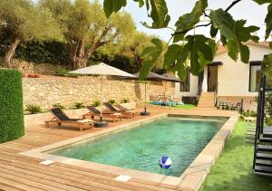 a swimming pool in a yard with chairs and an umbrella at La Villa d’Emma in Mougins