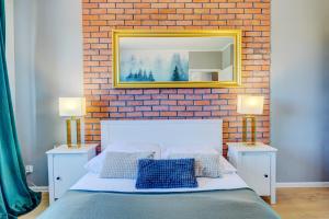 a bedroom with a brick wall and a bed with two lamps at Allure Nautica Aparthotel in Szczecin