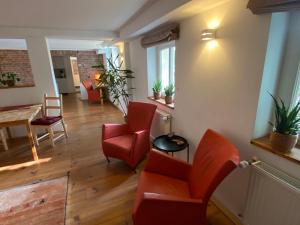 a living room with red chairs and a table at Historisch Pand in Spechtholzhock