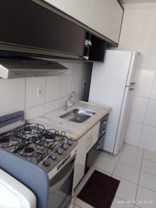a kitchen with a stove and a sink and a refrigerator at Ap ótima localização in São José dos Campos