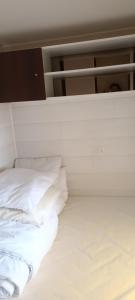 białe łóżko z białą pościelą i poduszkami w obiekcie mobil home 6 places w mieście Crots