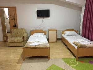 una camera con due letti e una sedia e una televisione di Hotel Diplomat a Struga