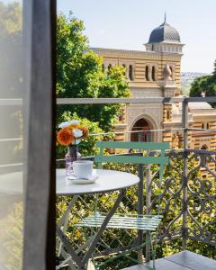 a table with a cup of coffee and flowers on a balcony at Alma Boutique Hotel in Tbilisi City