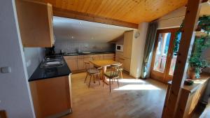 cocina con mesa, sillas y fregadero en Montafon Valley Apartments, en Sankt Gallenkirch