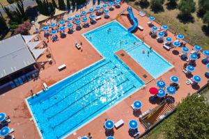 an overhead view of a large swimming pool with blue umbrellas at Villaggio Orizzonte in Riotorto