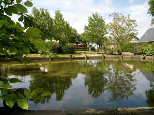 un estanque en un parque con una valla y árboles en Gite Caillebourg Normandie, en Saint-Martin-aux-Arbres