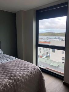 um quarto com uma cama e uma grande janela em Rom m/bad i Bodø sentrum em Bodø