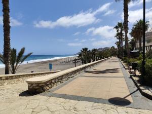 une passerelle à côté d'une plage bordée de palmiers dans l'établissement Casa del Sol - Vera Playa Laguna Beach, à Vera