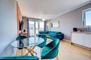 sala de estar con mesa de cristal y sillas verdes en Allure Nautica Aparthotel en Szczecin