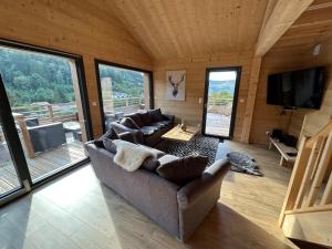 ein Wohnzimmer mit Sofas und einem Flachbild-TV in der Unterkunft Chalet Victorine, vue imprenable avec spa in Gérardmer