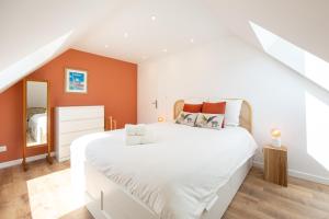 a bedroom with a large white bed with orange walls at Duplex Petit-Fort proche plage in Gravelines