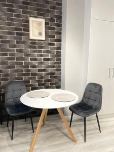 een tafel en twee stoelen voor een bakstenen muur bij Apartament Poezji A39 Grey in Gliwice