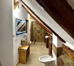 an attic bathroom with a sink and a toilet at Casa de Lemn Arpasu de jos in Arpaşu de Jos