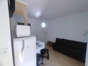 - un salon avec un canapé et un four micro-ondes dans l'établissement Apartamento Frente da Praça Central com 01 Vaga Garagem, à Poços de Caldas