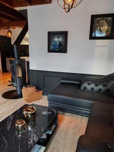 sala de estar con sofá de cuero negro y chimenea en Ty Ker Spa Brocéliande, en Saint-Malon-sur-Mel