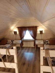ゴウダプにあるDomek Nad Stawemのベッド2台、窓が備わるログキャビン内の客室です。