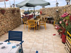 a patio with chairs and tables and an umbrella at Ta' Lorenzo Farmhouse 2 in San Lawrenz
