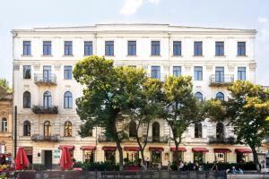 a large white building with trees in front of it at Alma Boutique Hotel in Tbilisi City