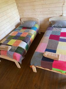 two beds in a room with wooden floors at Žubites - 3 in Bērzgale +11 photos