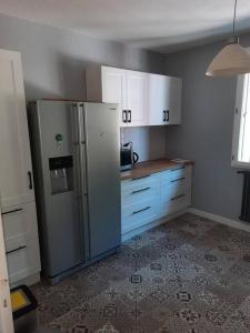 a kitchen with a stainless steel refrigerator and white cabinets at Maison au Calme, prés du centre Parking Privé in Angoulême
