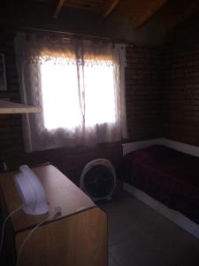 a room with a window and a desk with a fan at La Lechuza in El Volcán