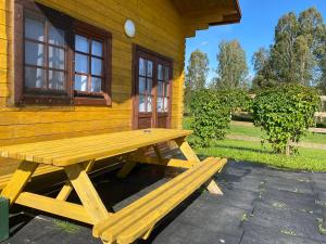 una mesa de picnic de madera sentada fuera de una cabaña en Žubites - 3, en Bērzgale