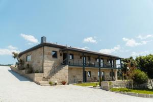 a stone house with a balcony on a road at Casa de Algar - Enoturismo in Castelo de Paiva