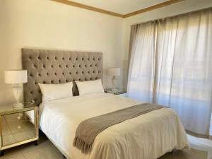 a bedroom with a large bed and a window at Siena Sun Luxury Apartment 6 in Midrand +4 photos