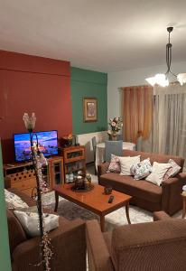 a living room with two couches and a flat screen tv at Cozy place in Kozani