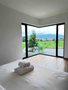 um quarto branco com uma cama com uma toalha em The Rice Villas วิวทุ่งนาภูเขา 2King beds& hot Bathtub em San Sai