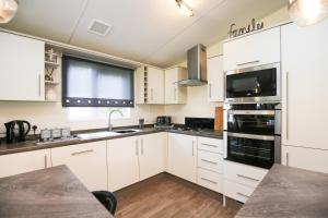 una cucina con armadietti bianchi ed elettrodomestici neri di Woodlands 55 Cresswell a Ellington