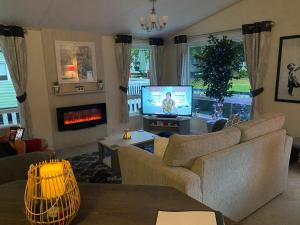 a living room with a couch and a tv at Woodlands 55 Cresswell in Ellington