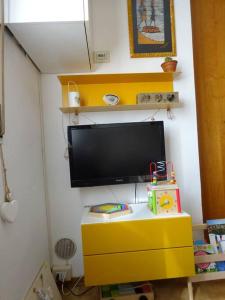 a living room with a tv and a yellow dresser at Casa in collina, vista mare. in Nibbiaia