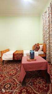 Zimmer mit 2 Betten und einem Tisch mit einem roten Tischtuch in der Unterkunft Moonshine Home stay in Srinagar