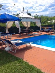 a pool with chairs and umbrellas next to a swimming pool at B&B Il Portico in Sarzana