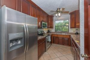 La cuisine est équipée d'armoires en bois et d'un réfrigérateur en acier inoxydable. dans l'établissement Pineapple Villa 531 condo, à Roatán