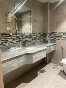 La salle de bains est pourvue d'un grand lavabo et de toilettes. dans l'établissement فندق دان البلاتيني, à Médine