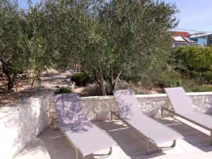 duas cadeiras brancas sentadas num pátio com árvores em apartments Marina,Bikić em Marina