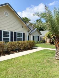 a house with a palm tree next to a sidewalk at Spacious Home near Gulf Shores & Orange Beach in Foley