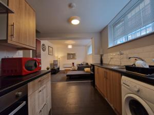 a kitchen with a microwave and a living room at Primos Suite - Stylish 1 Bedroom in Wallsend in Old Walker