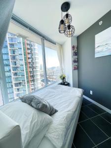 um quarto com uma cama branca e uma grande janela em Downtown 4bd 2ba View Skytrain 2 Free Parking em Vancouver