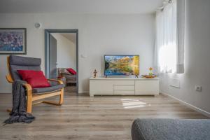 uma sala de estar com uma televisão e uma cadeira em appartamento LA SORTIVA em Cles