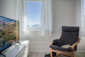uma sala de estar com uma cadeira e uma televisão de ecrã plano em appartamento LA SORTIVA em Cles