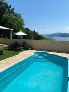 a blue swimming pool with a table and an umbrella at Pousada Artelai in Angra dos Reis