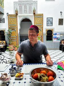 a man sitting at a table with a bowl of food at Riad Green House in Fez