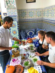 un gruppo di persone che si trovano intorno a un tavolo con cibo di Riad Green House a Fes